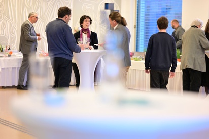 Eine Gruppe von Menschen unterhält sich vor einem festlich gedeckten Buffet.  © ESF / Christopher Glanzl