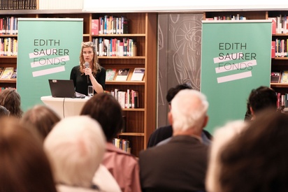 Eine Frau spricht in einer Bibliothek, eine Menschengruppe h&ouml;rt ihr zu. &copy; ESF / Christopher Glanzl