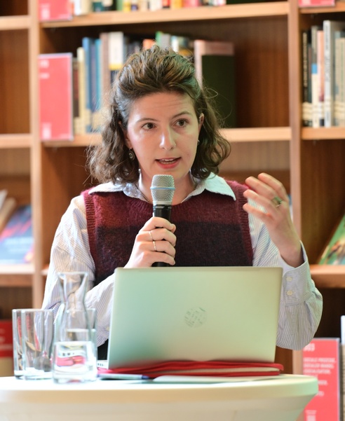 Eine Frau mit Mikro in der Hand hält in einer Bibliothek eine Rede. © ESF / Christopher Glanzl