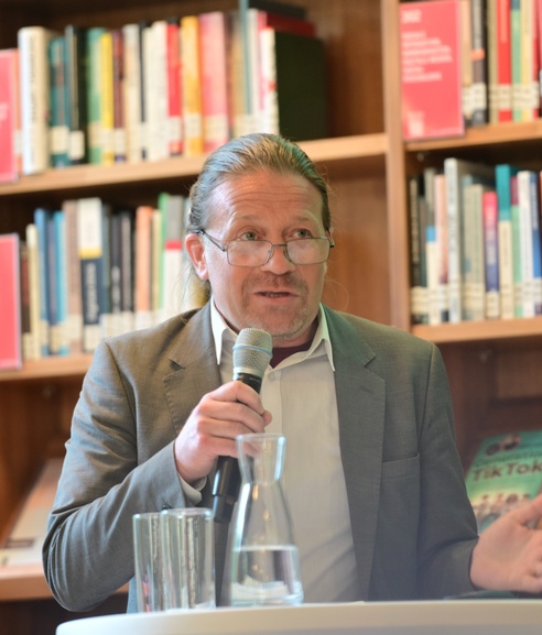 Eine Mann mit Mikro in der Hand hält in einer Bibliothek eine Rede. © ESF / Christopher Glanzl
