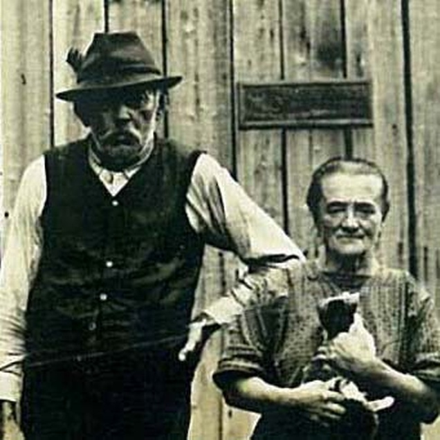 Auf dem Bild ist eine Magd, mit einer Katze auf dem Arm und ein Knecht zu sehen, die vor einem Schuppen stehen. © Museum Arbeitswelt Steyr